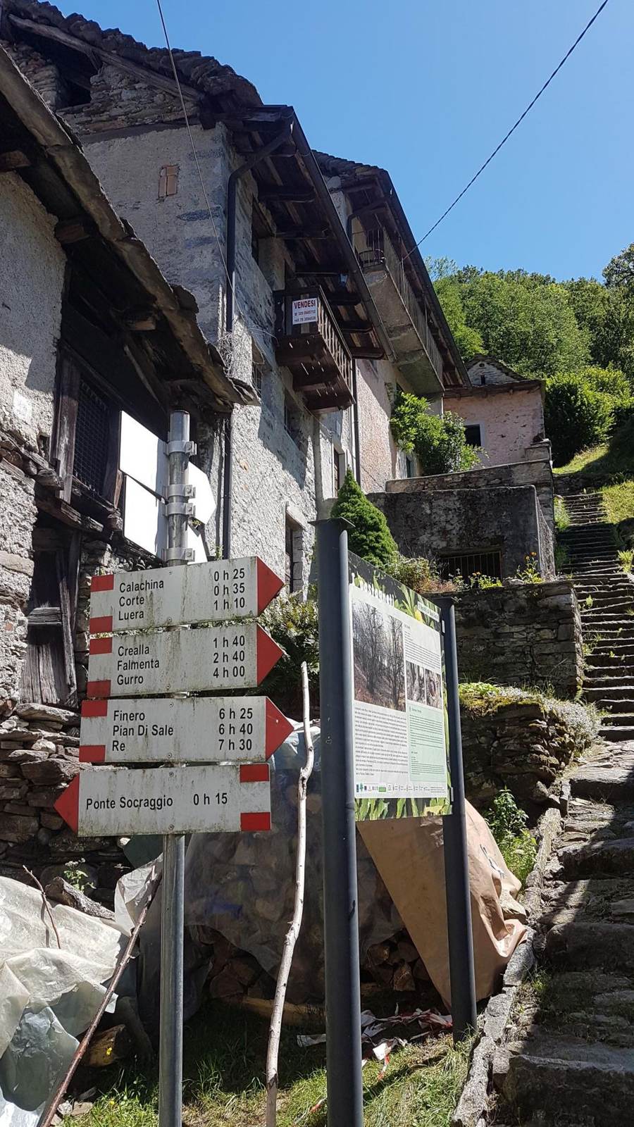 Old stone building with hiking route signs in a village above Cannobio