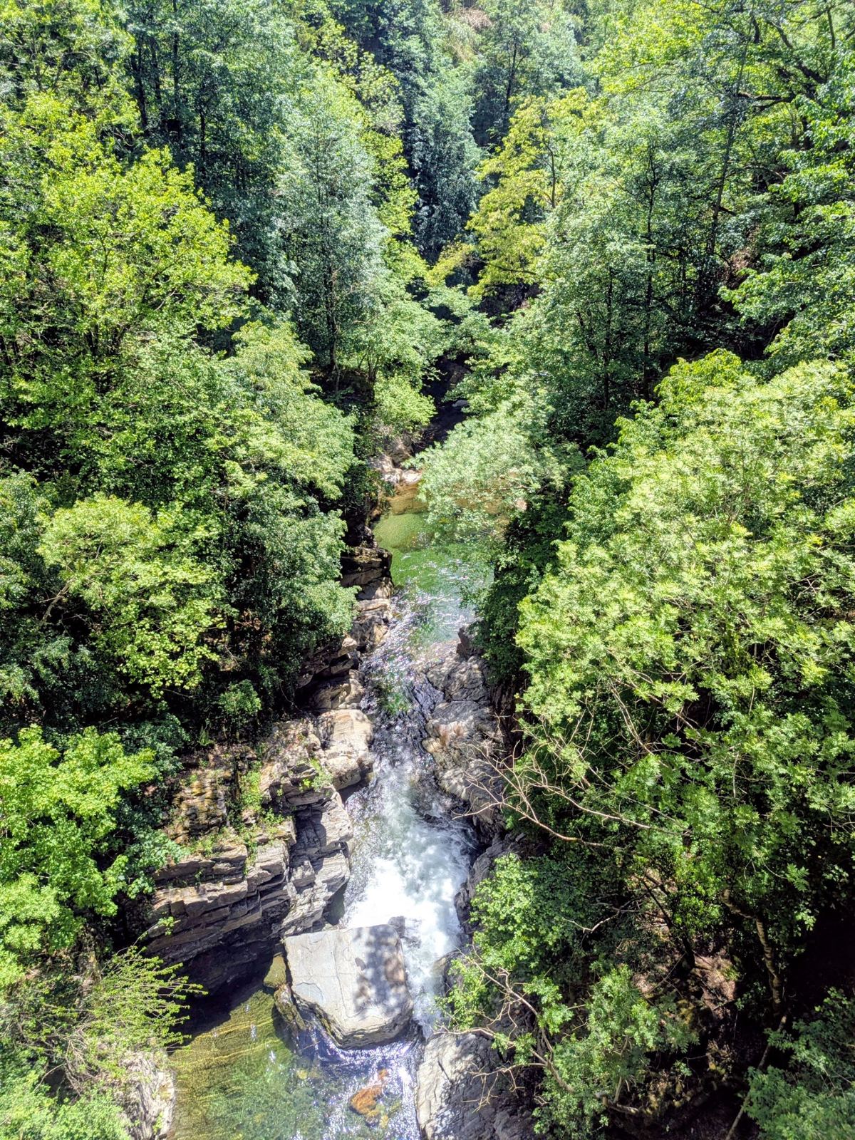 Looking straight down at a white-water stream running through a narrow rocky gorge, seen from a bridge