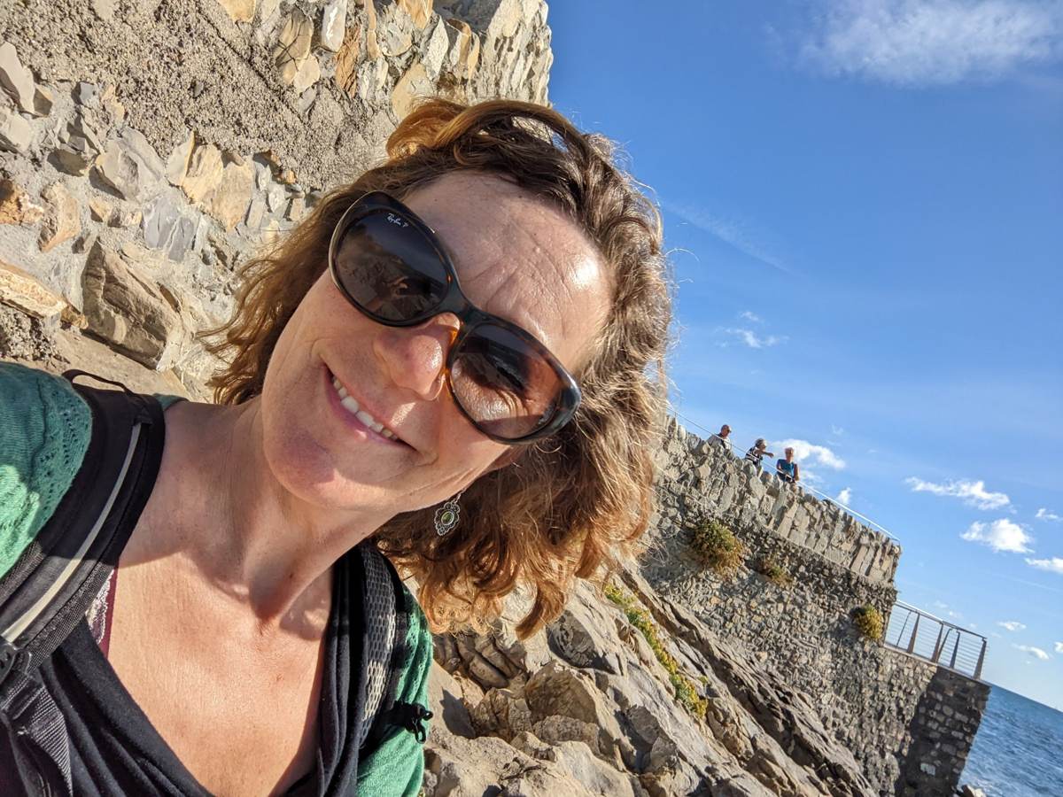 Kevin's wife at a clifftop stop along the Ligurian coast path, sea and rocks in the background