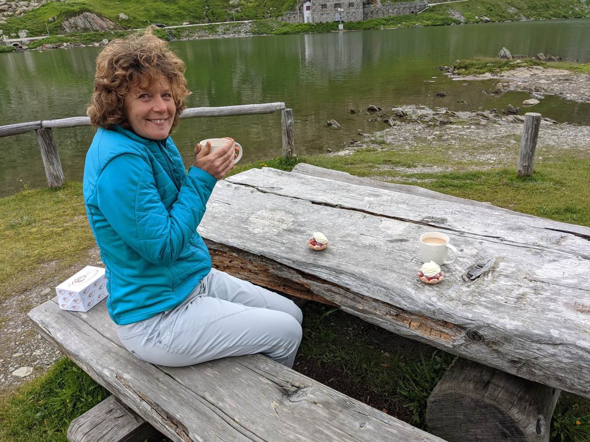Kevin's wife at a picnic table by the summit lake at Grand St Bernard Pass