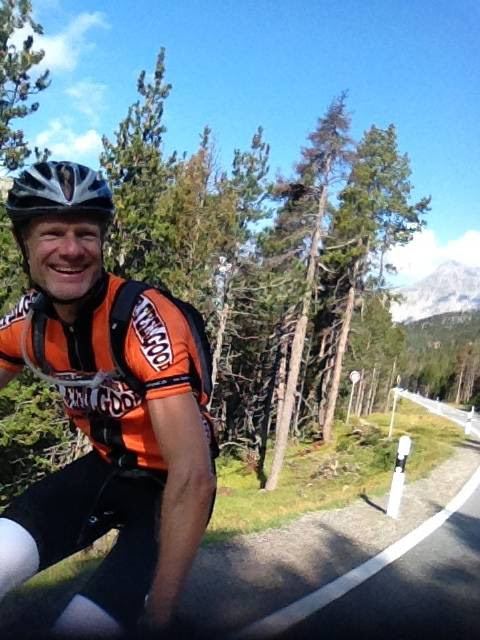 Kevin riding in an orange Mr Feelgood cycling jersey on the road up the Pass dal Fuorn, Switzerland
