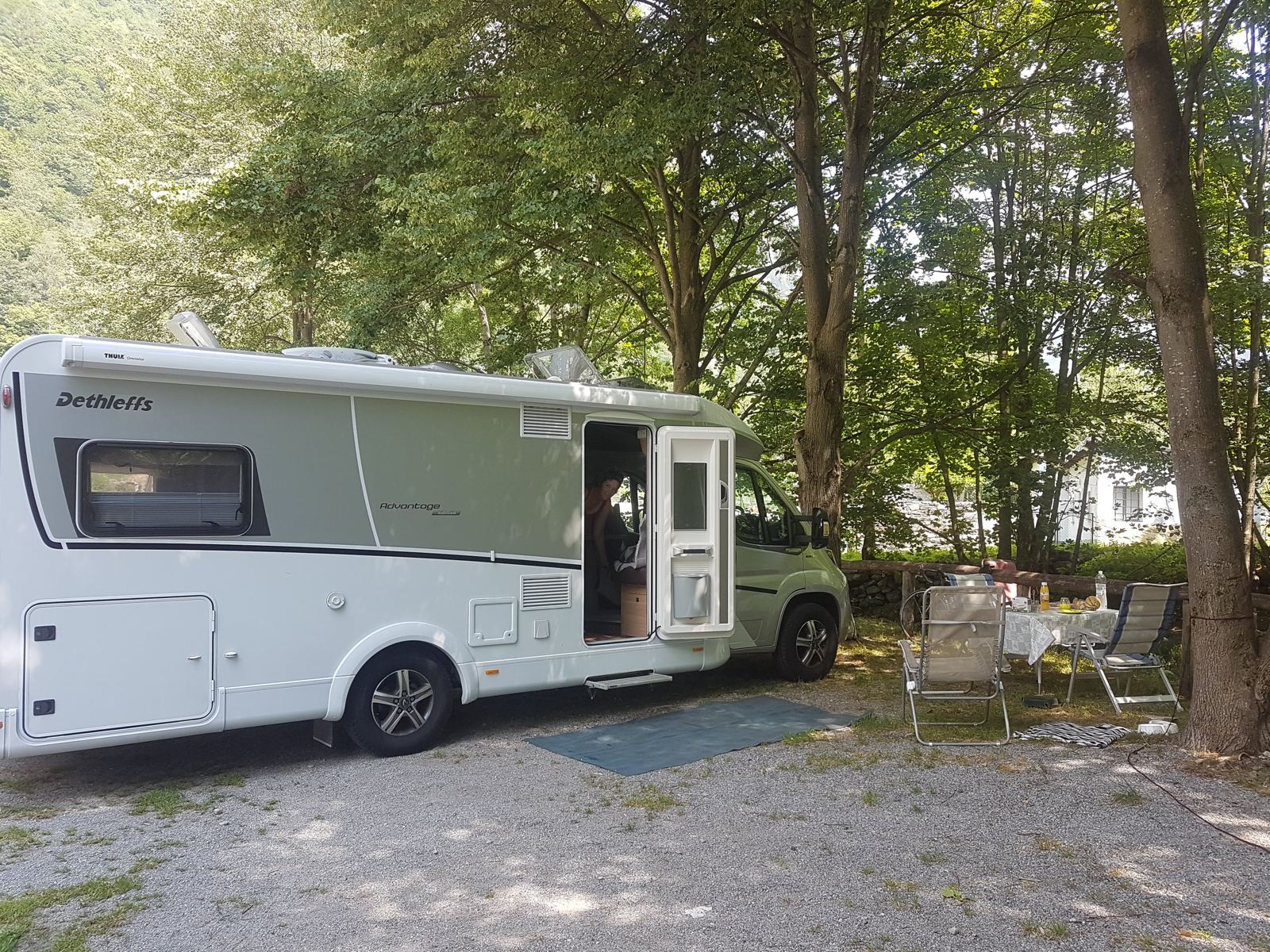 Kevin's Dethleffs motorhome parked at a shaded riverside campsite in the Verzasca Valley